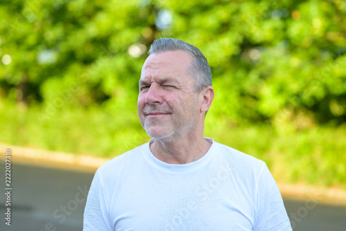 Thoughtful mature man squinting outdoors portrait