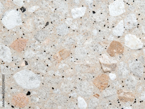 Close-up of a terrazzo surface featuring a mix of white, beige, and black stone chips embedded in a light, neutral base.