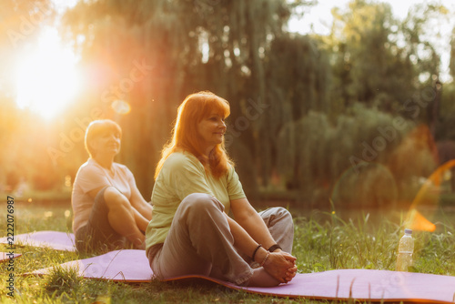Senior women practicing yoga in park at sunset