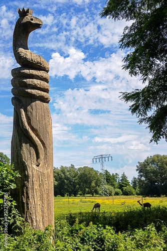 raddusch, deutschland - holzfigur einer schlange mit krone und alpakas im hintergrund 