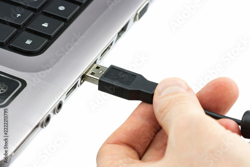 Close-up of a person connecting a USB cable to a laptop computer, showing data transfer, charging, and modern device connectivity on a white background