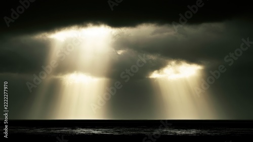 Dramatic sunbeams pierce stormy clouds over dark ocean at dusk