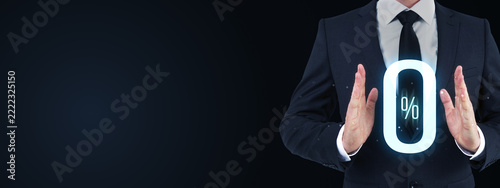Businessman presenting a glowing zero percent symbol in a dark corporate scene with generous copy space for finance, marketing, and business concepts.