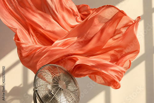 Coral silk caught by airflow above a metal fan