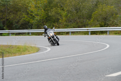 biker on a custom classic motorcycle rides down the road, road traffic