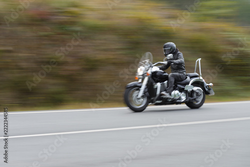 biker on a custom classic motorcycle rides down the road, road traffic