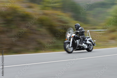 biker on a custom classic motorcycle rides down the road, road traffic