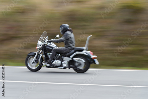 biker on a custom classic motorcycle rides down the road, road traffic
