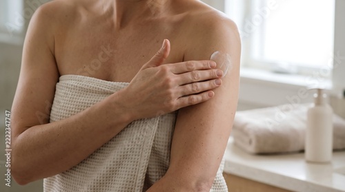 Woman applying moisturizing lotion to her arm after shower in a