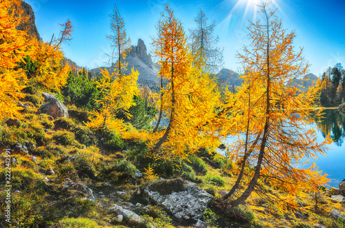 Amazing autumn view of  Lake Federa  at sunrise with majestic rocky mount and colorful trees glowing sunlight in Dolomites