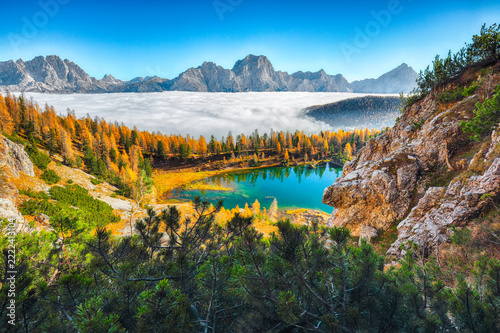 Breathtaking  aerial view of  crystal clear Lake Federa in Dolomites Alps under sunlight in mist and fog