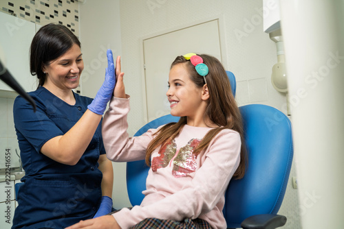 Fotografie A female dentist and a smiling young girl give each other a high five in the den
