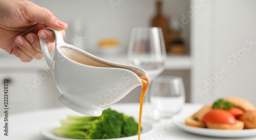 Hand pouring sauce over a plated meal