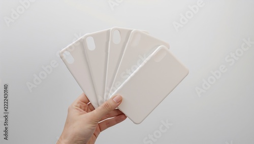 Hand holding a set of white plastic cutting boards over a plain background