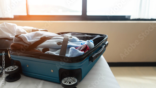 Traveler prepares luggage for a vacation trip in a bedroom. Open suitcases on the bed highlight travel packing, vacation preparation, holiday planning, and organizing luggage before a trip.