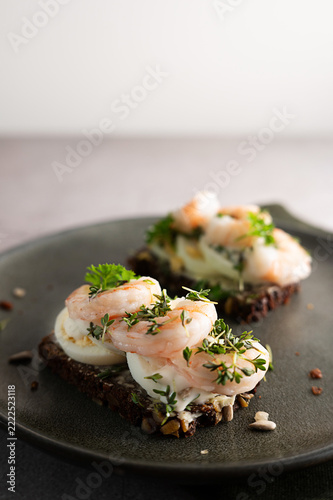 Seeded rye bread with egg, shrimps, and garden cress garnish.