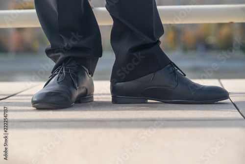 Legs of a businessman in fashionable shoes standing outdoors in the city