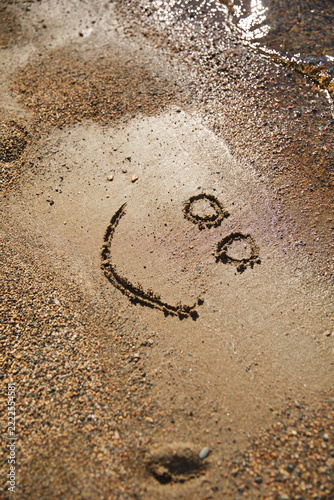 A hand-drawn smiley face in the sand at a beach in Ontario, Canada.