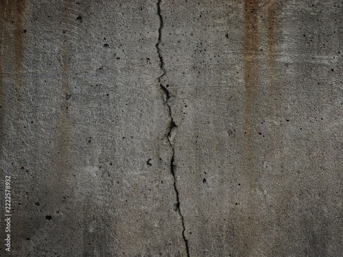 Cracked concrete wall with rain streaks and cavities.