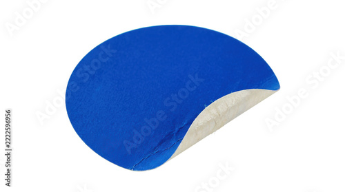 Single blue round sticker label with a partially peeled edge, subtle crumpled paper texture, smooth printable center, and realistic adhesive backing, photorealistic packaging accessory photography,