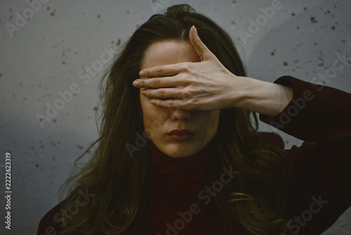 Woman covers face in fragmented portrait of emotional distress
