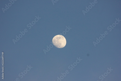 The moon is visible in the daytime sky with a clear blue sky