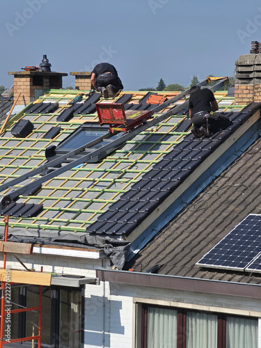 Ouvriers qui rénovent la toiture d’une maison pour isolation et remplacement des tuiles