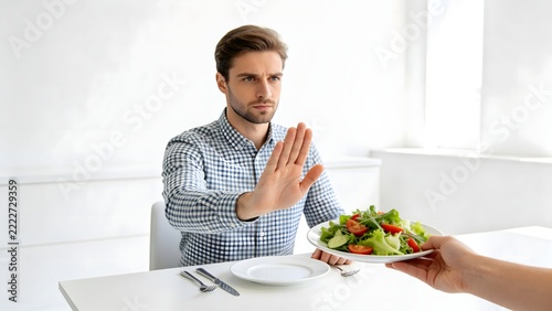 Man Refusing Offered Plate Of Fresh Salad At Table