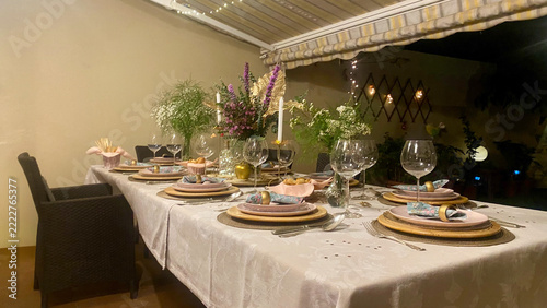 Elegant Christmas dinner table setting with pink plates, wine glasses and festive lights