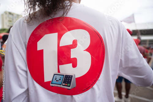 Person with a large sticker of the number thirteen and a voting machine on their back