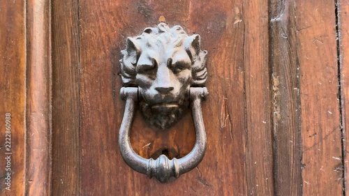 Antique bronze lion head door knocker on a weathered wooden door, Rome, Italy