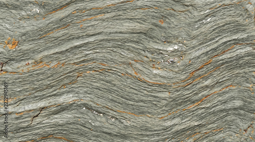 Contorted wavy foliated metamorphic rock texture with rusty orange mineral seams