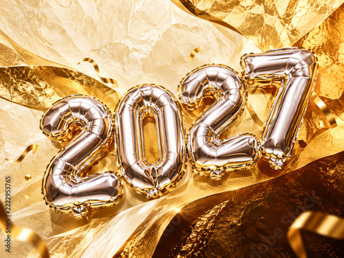 Silver 2027 foil balloon numbers laying on golden textured fabric with curly ribbons around.