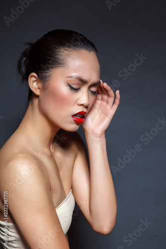 A portrait of a beautiful, restrained, elegant woman. Her smooth hair is neatly combed back. A bright red lipstick contrasts with the soft, neutral makeup.