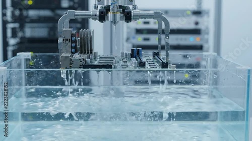 Robotic arm submerging a motherboard into a cooling tank.