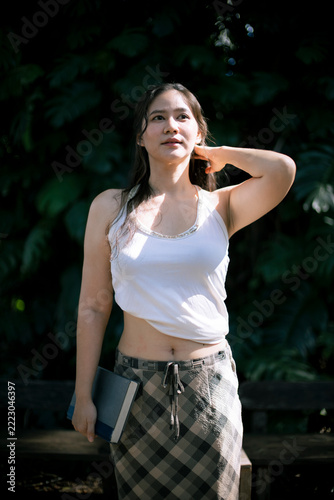Young woman standing outdoors in casual clothing holding book and looking away