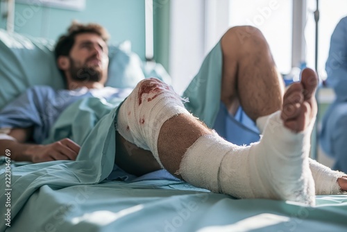 Injury recovery process in hospital setting involving man with leg injury and bandages