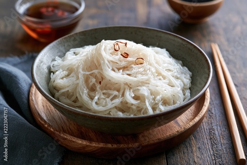 Keto shirataki noodles served in a bowl with chopsticks on a wooden table with sauces in the background for low carb meals