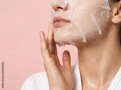 Young woman applying a sheet mask on her face
