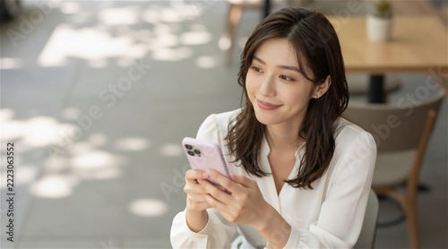 Smiling Young Japanese Woman in White Blouse Using Smartphone at Outdoor Cafe Terrace