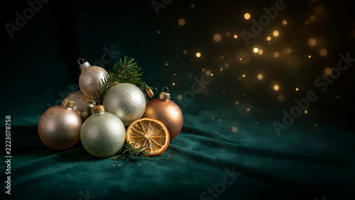 Elegant Christmas Glass Baubles in Muted Festive Colors Arranged on Rich Green Velvet with Golden Fairy Light Bokeh and Spacious Copy Area