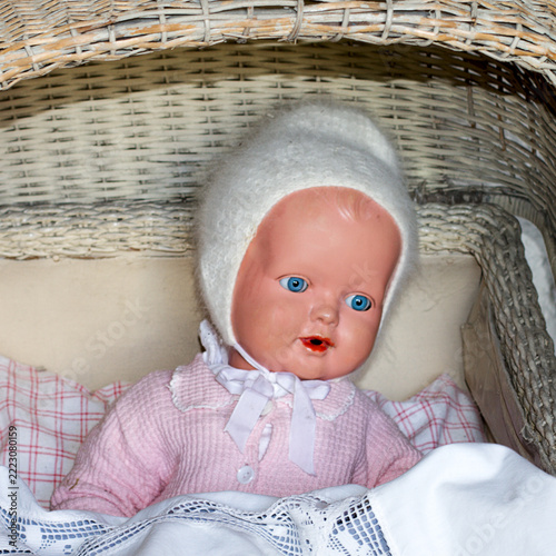 old-fashioned doll with blue eyes and a wool hat in a pram

