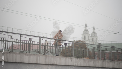 Photography •  Angel man standing on bridge with church background and copy space