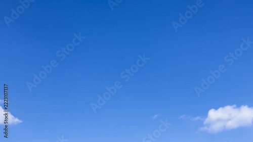 Time lapse panoramic view of drifting cumulus clouds moving across clear blue sky over open horizon at midday