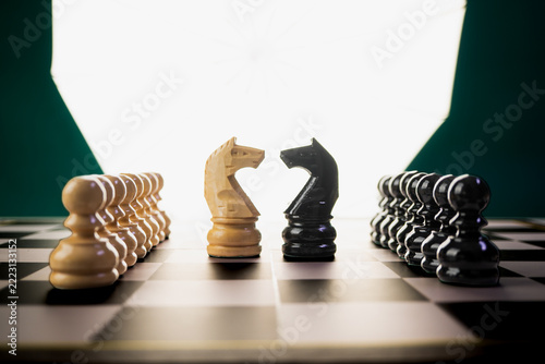 Fotografie White and Black Knight Chess Pieces Facing Off on Chessboard