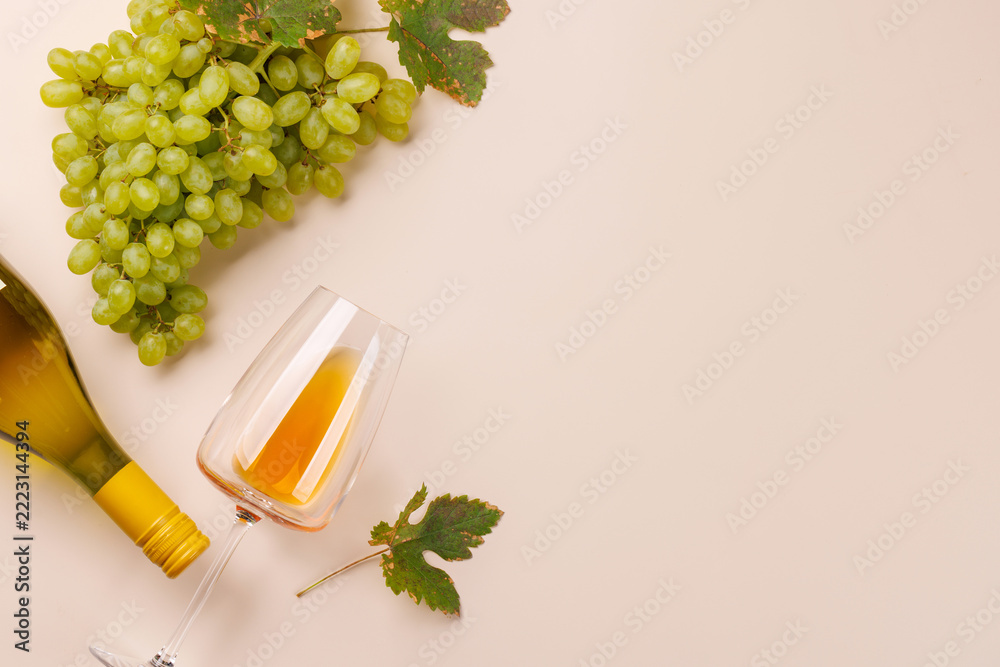 Fototapeta premium White wine glass and green grapes framing pastel copy space