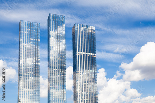 Three skyscraper towers stand against a cloudy sky
