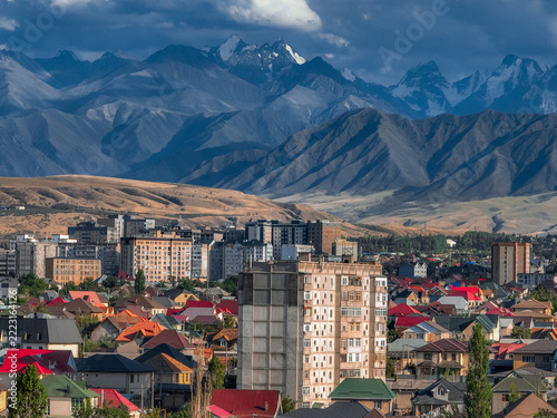 View of multi story residential buildings and suburban houses nestled under steep rugged mountain slopes