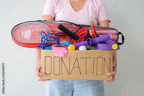 Donation box with sports equipment. The volunteer is holding a cardboard box with items for sports activities.