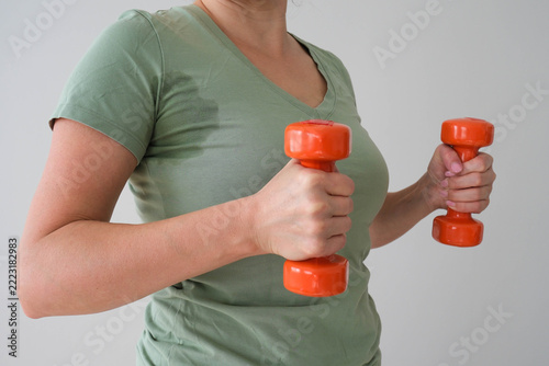 The woman has a wet sweat stain on her T‑shirt. A person is exercising and has become sweaty.
